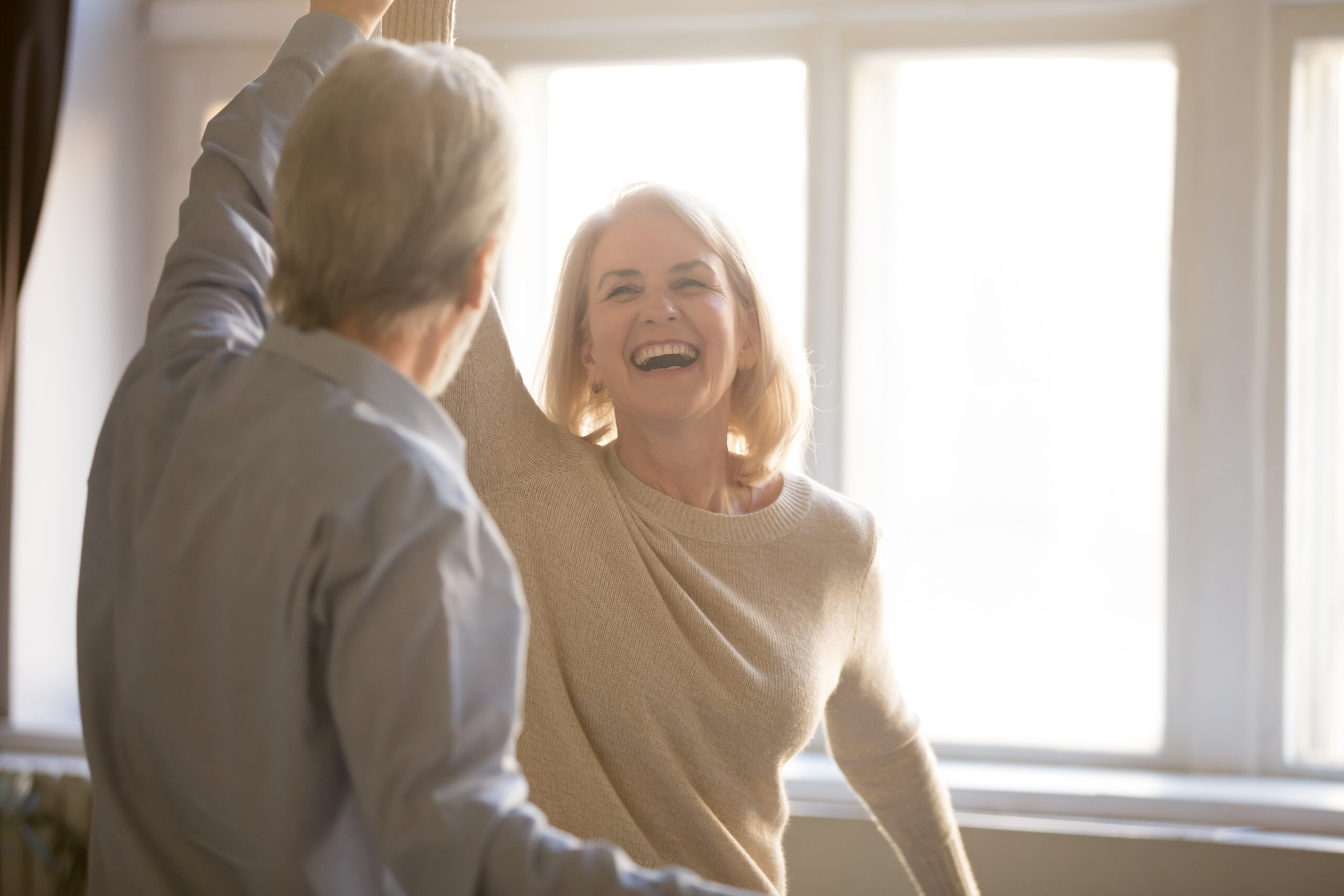 Elderly woman laughing indoors after oral treatment at Oak Mountain Denture and Implant Center.