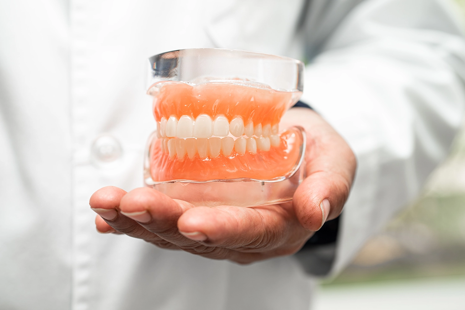 Dentist holding full upper and lower dentures for demonstration - Oak Mountain Denture and Implant Center.