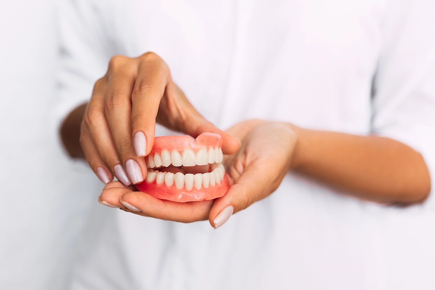 Dentist holding full denture model for patient education