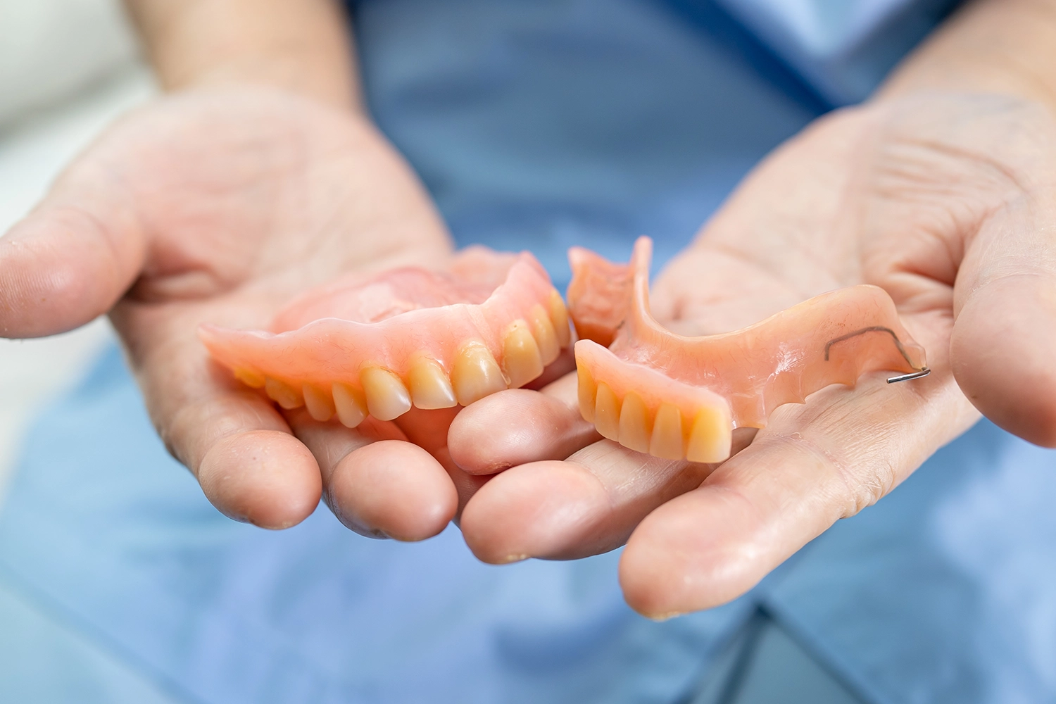Dental professional holding removable dentures in hand
